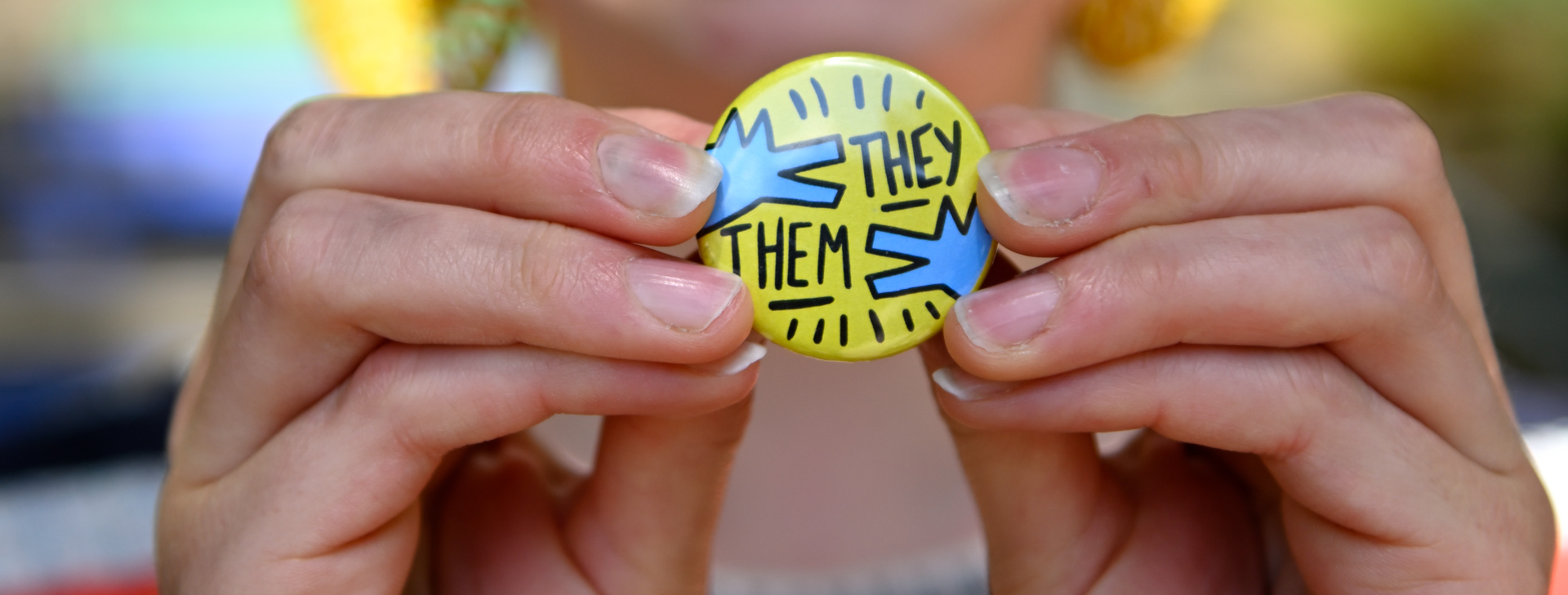Student holding a they-them pronoun badge